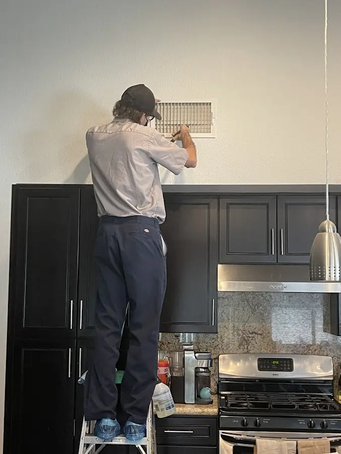 Technician inspecting an air vent during HVAC service in Senoia